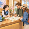 観光案内カウンターで旅行者が地図を見ながらスタッフへ相談するイメージイラスト